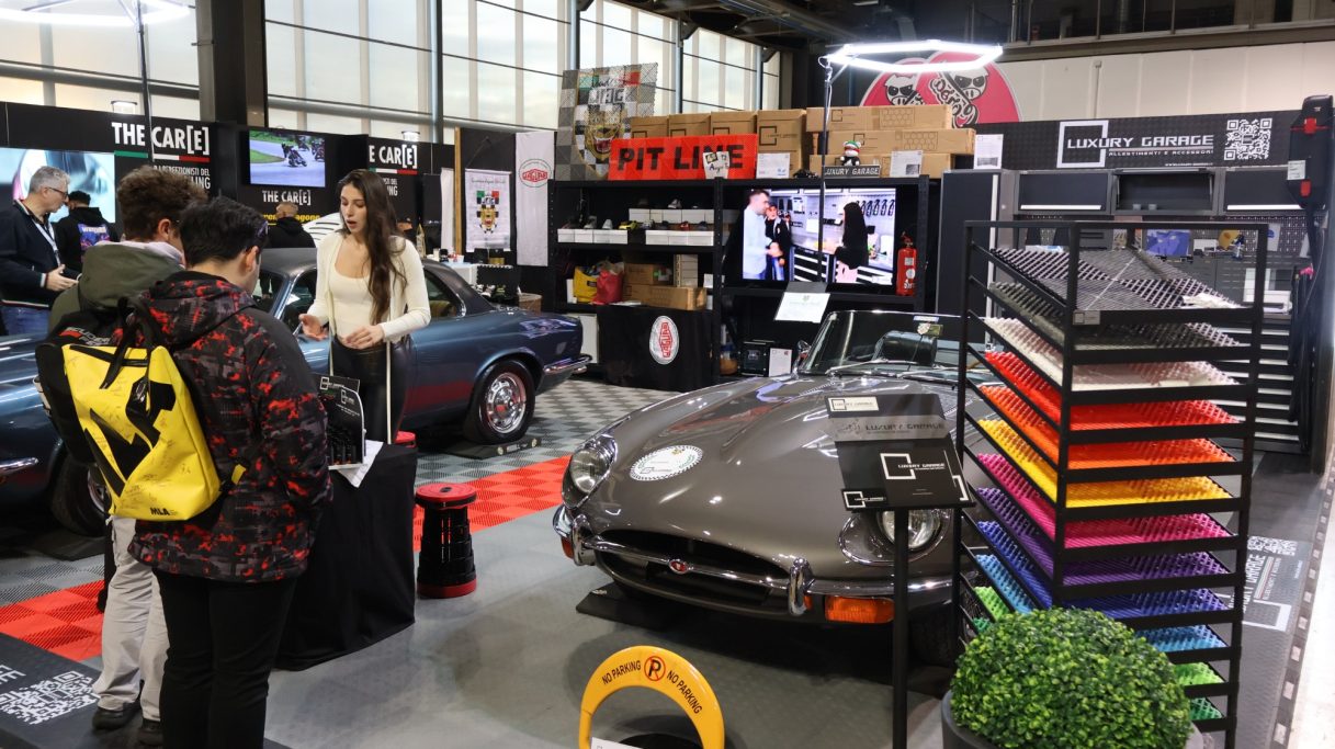 Stand showcasing a vintage car, with people browsing and colorful displays in the background.