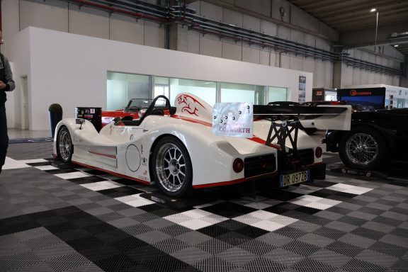Racing car with a white and red design, positioned on a checkered floor.
