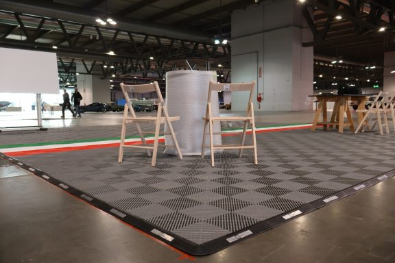 Set of chairs and a podium on a patterned floor in an empty exhibition hall.