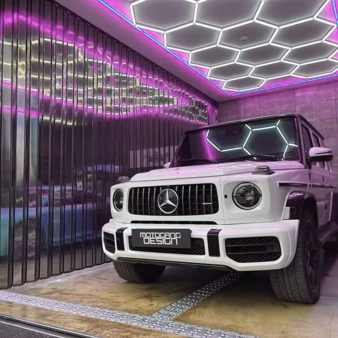Mercedes G-Class SUV parked in a modern garage with hexagonal neon lighting.