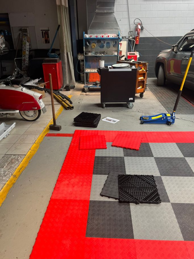 Installazione Chiavi in Mano Area with red and black mats, tools, and equipment scattered on the floor.