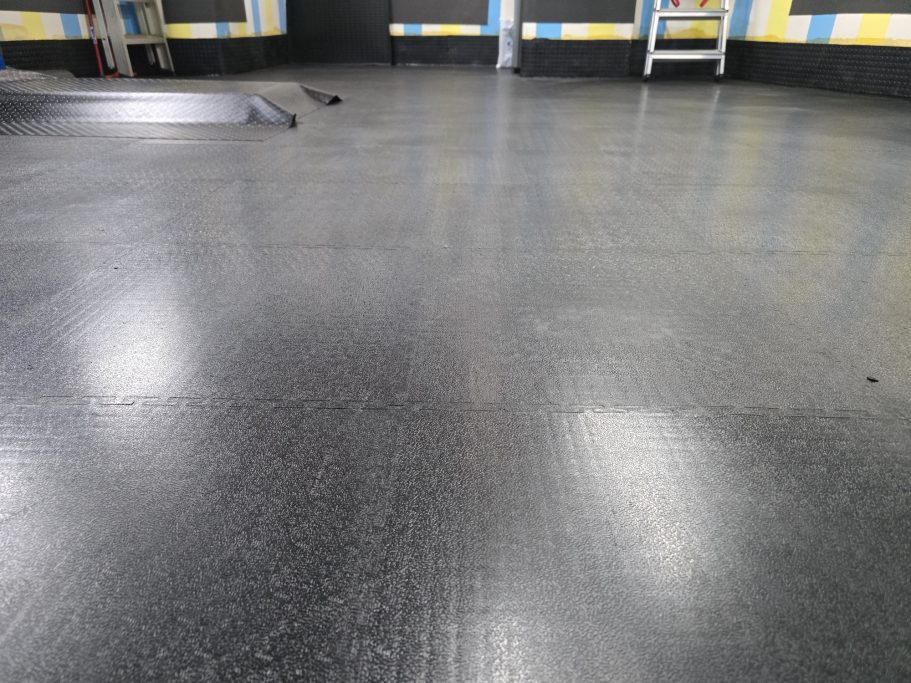 PAVIMENTO PVC AD INCASTRO 40T/MQ Pavimento nero lucido con riflessi, tipico di un ambiente interno.