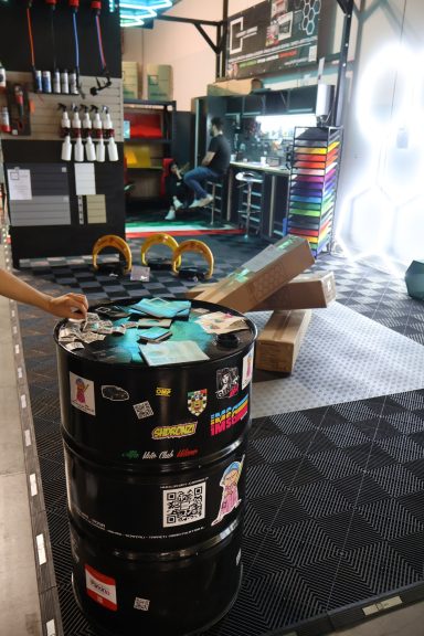 Barrels decorated with stickers in a workshop setting with tools and equipment visible.