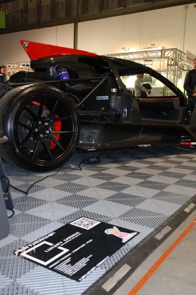 Automobile with a sleek, black design and red accents displayed on a checkered floor.