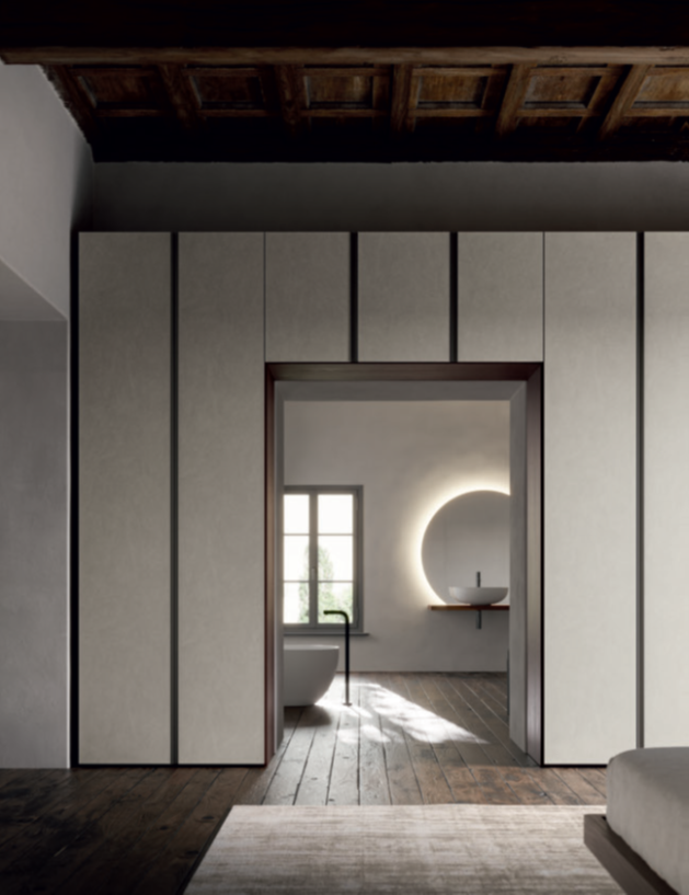ARMADIO CON PASSAGGIO Modern interior with a minimalistic design featuring a circular light and wooden accents.