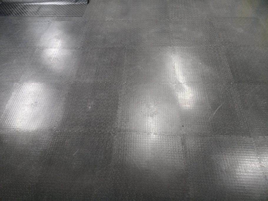 Pavimento Industriale per Magazzino Smooth, dark floor with reflections and a subtle sheen.
