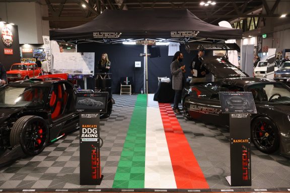 Esposizione di auto sportive su un pavimento a scacchi con un tema tricolore italiano.