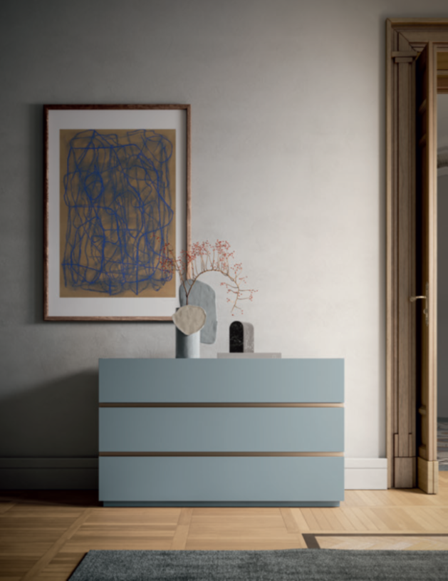 CASSETTIERA TRE CASSETTI Modern light blue dresser with wooden accents, framed artwork, and decor items.