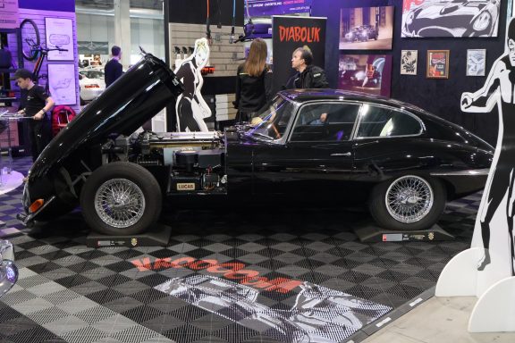 Auto vintage nero con il cofano sollevato, esposto in una mostra automobilistica.