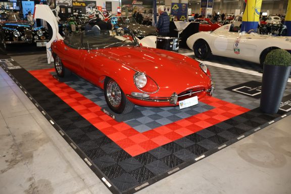 Auto sportivo rosso in esposizione su un pavimento a scacchi nero e rosso.