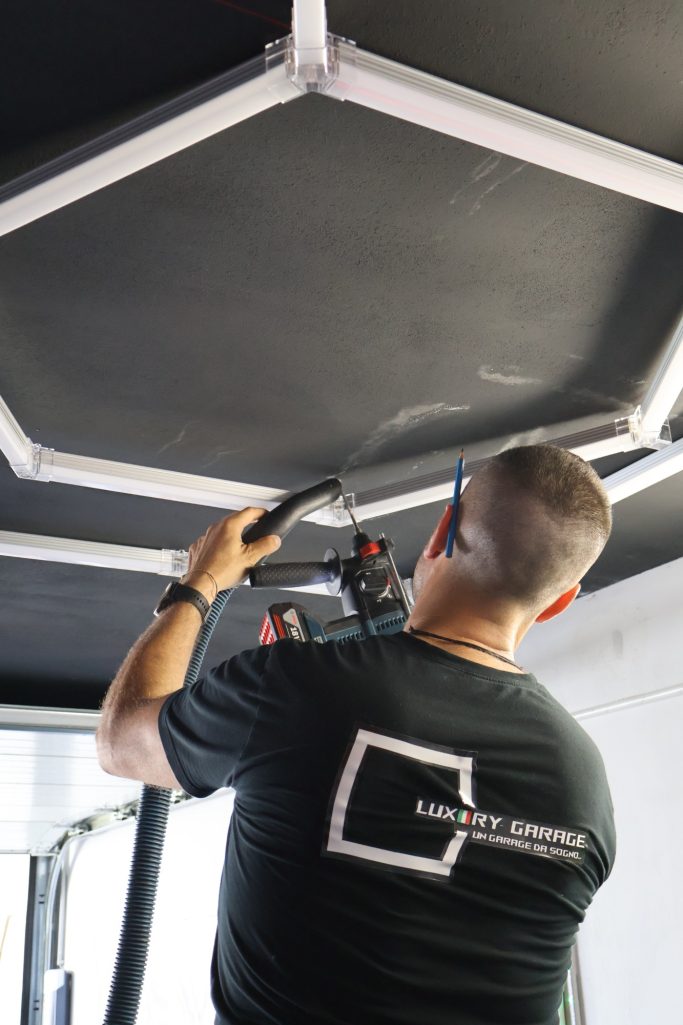 Posa e Installazione Professionale Uomo che fissa un telaio su un soffitto con uno strumento elettrico.