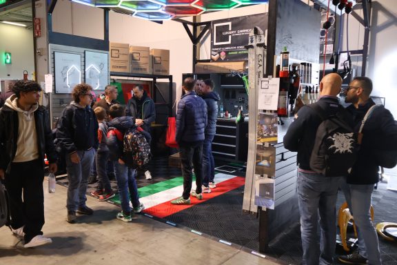 Persone che interagiscono in un evento, con una bandiera italiana sul pavimento.