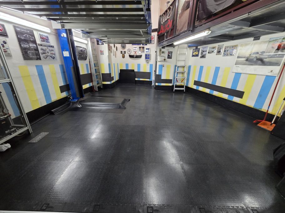 Spazio interno di un'area di lavoro con pavimento nero e pareti gialle e blu.