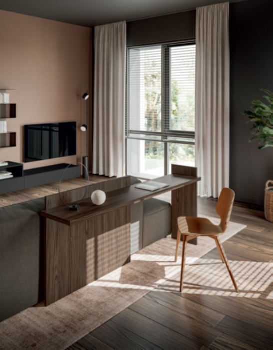MODULO SCRIVANIA PER DIVANO Modern office interior featuring a wooden desk, chair, and large windows with natural light.