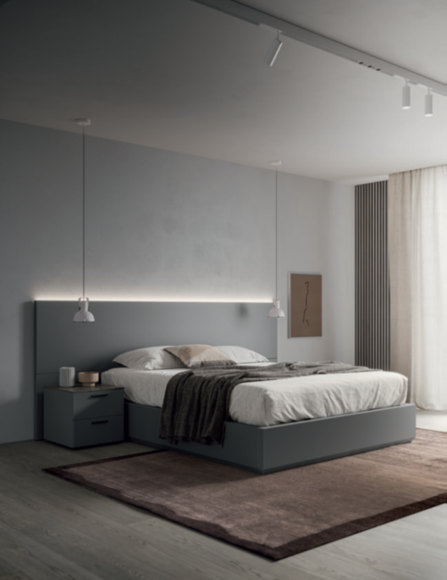 CAMERA DA LETTO SOFT Modern bedroom with a gray bed, nightstand, and soft lighting, featuring a cozy rug.