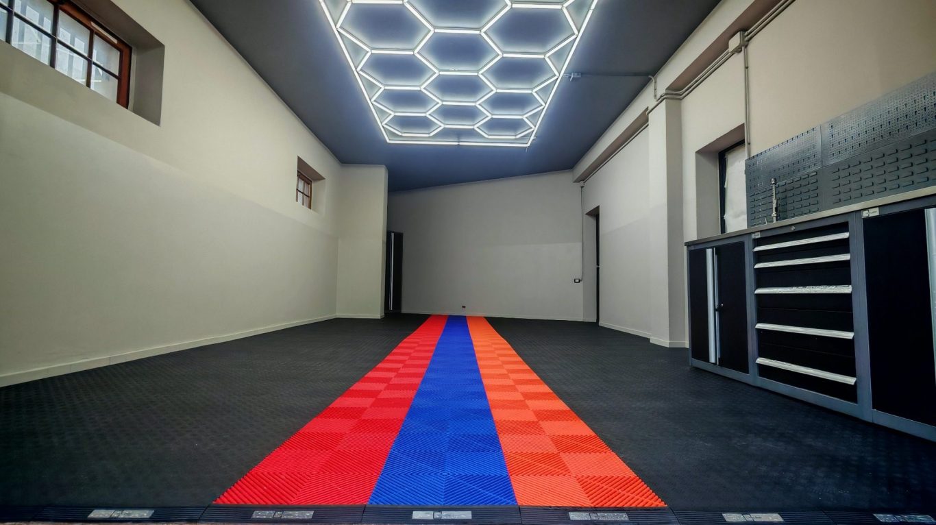 Empty room with a patterned floor featuring red and blue stripes and hexagonal ceiling lights.