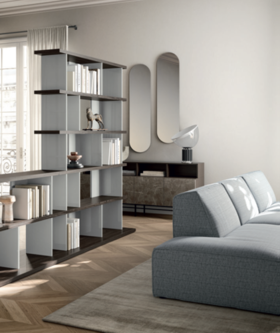 LIBRERIA BEND Soggiorno moderno con libreria, divano grigio e specchi decorativi.