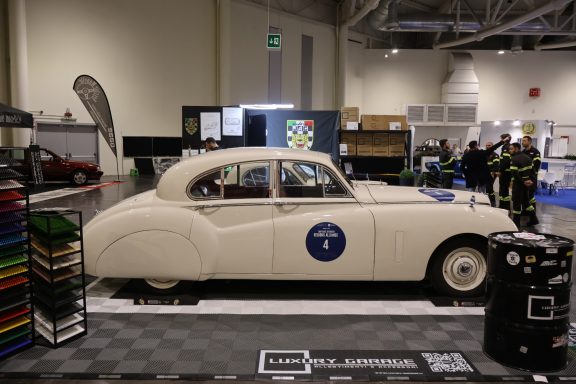 Auto d'epoca di colore bianco con logo blu, esposto a un evento.