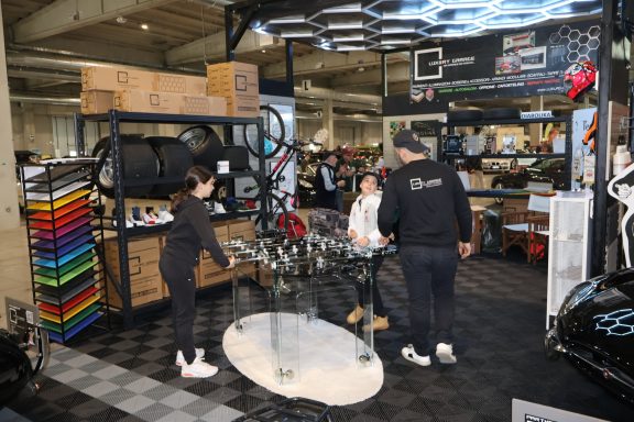 Stand at an auto show with people discussing car accessories and a display of colorful tools.