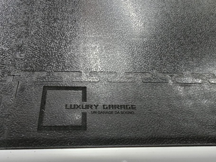 BORDO PAVIMENTO INDUSTRIALE Logo of Luxury Corner embossed on a textured black surface.