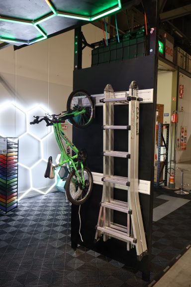 Bicycle hanging on a wall near a metal ladder in a modern, illuminated space.