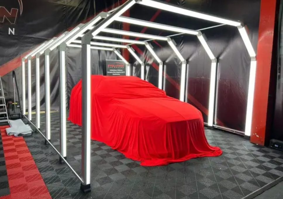 Auto coperto da un telo rosso all'interno di una struttura illuminata.