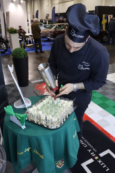 Chef decorating canapés with a piping bag at a culinary event.