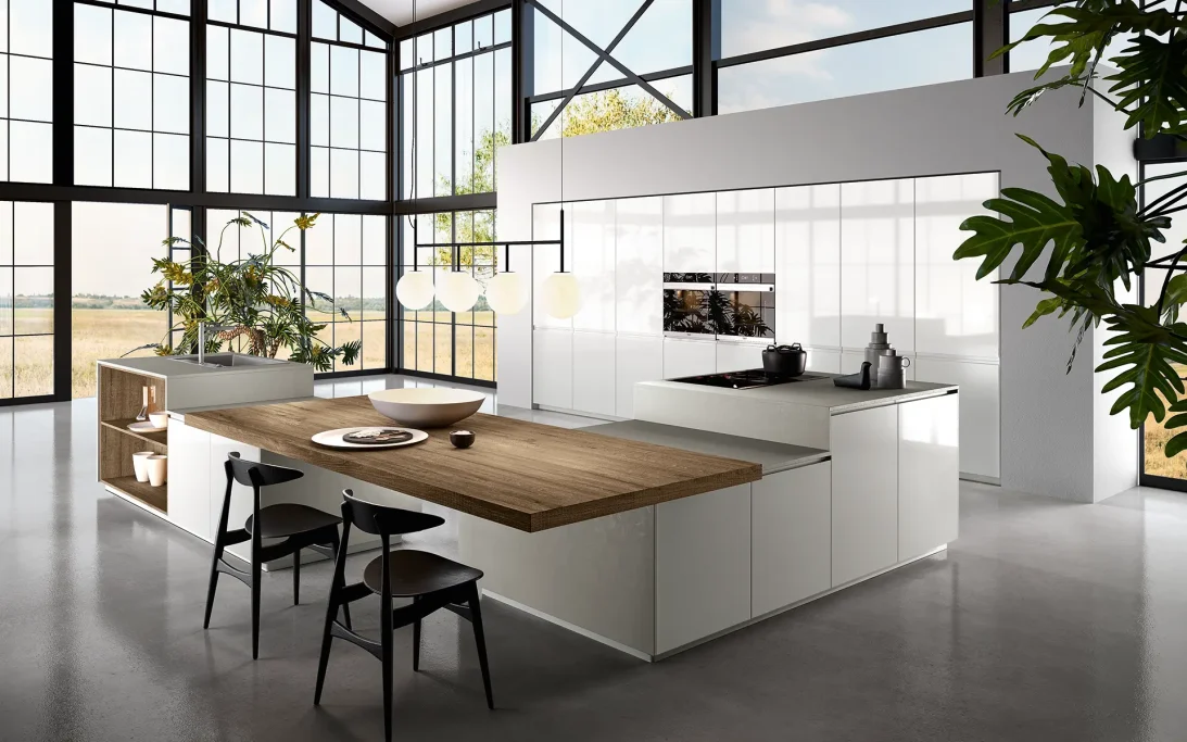 Cucina moderna con isola, armadi bianchi e finestroni a tutta altezza.