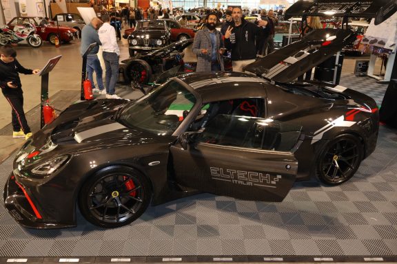 Auto sportiva nera con dettagli rossi esposta in un evento automobilistico.