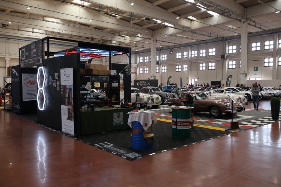 Esposizione di auto in un'area fieristica con stand decorato e vari veicoli.