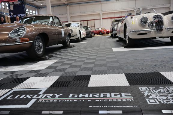 Classic cars lined up in a luxury garage featuring a checkered floor.