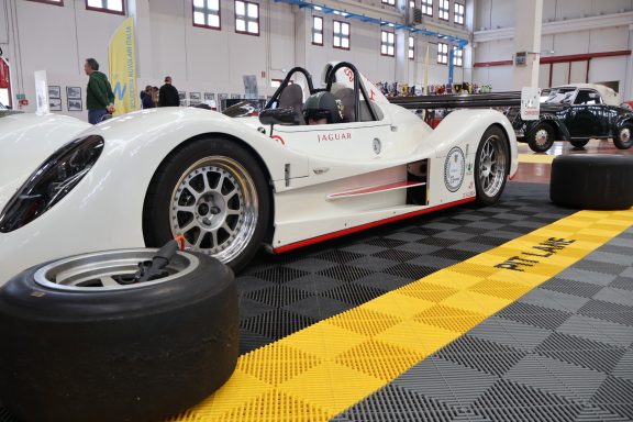 Auto da corsa bianco su pista gialla e nera, con pneumatici a lato.
