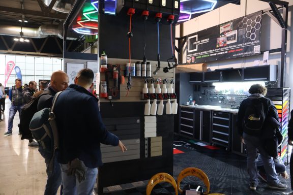 Attendees examine tools and equipment at a trade show display.