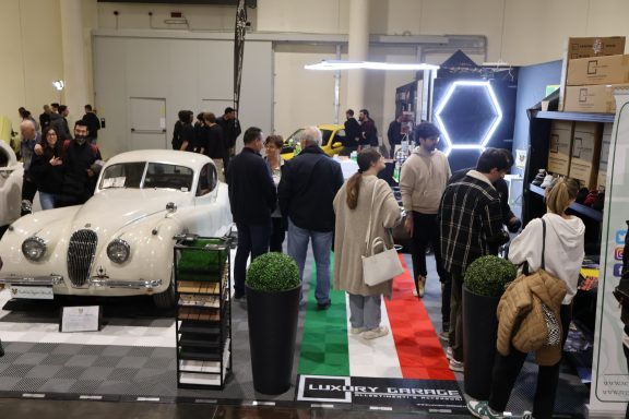 Fiera con auto d'epoca e visitatori che esplorano esposizioni.