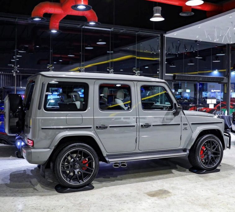 Cuscini Anti Ovalizzazione Pneumatici Fuoristrada grigio metallizzato con cerchi neri e dettagli rossi in un showroom moderno.