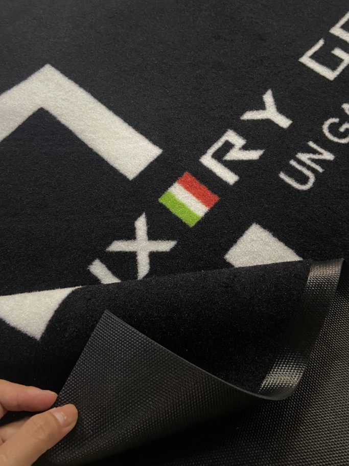 Tappeto con logo "Luxury" e bandiera italiana, bordi piegati visibili.