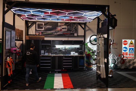 Laboratorio di lavoro con attrezzature, pavimento tricolore italiano e luci colorate.