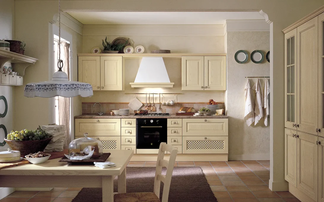 Cucina moderna con armadi chiari, tavolo e attrezzature da cucina.